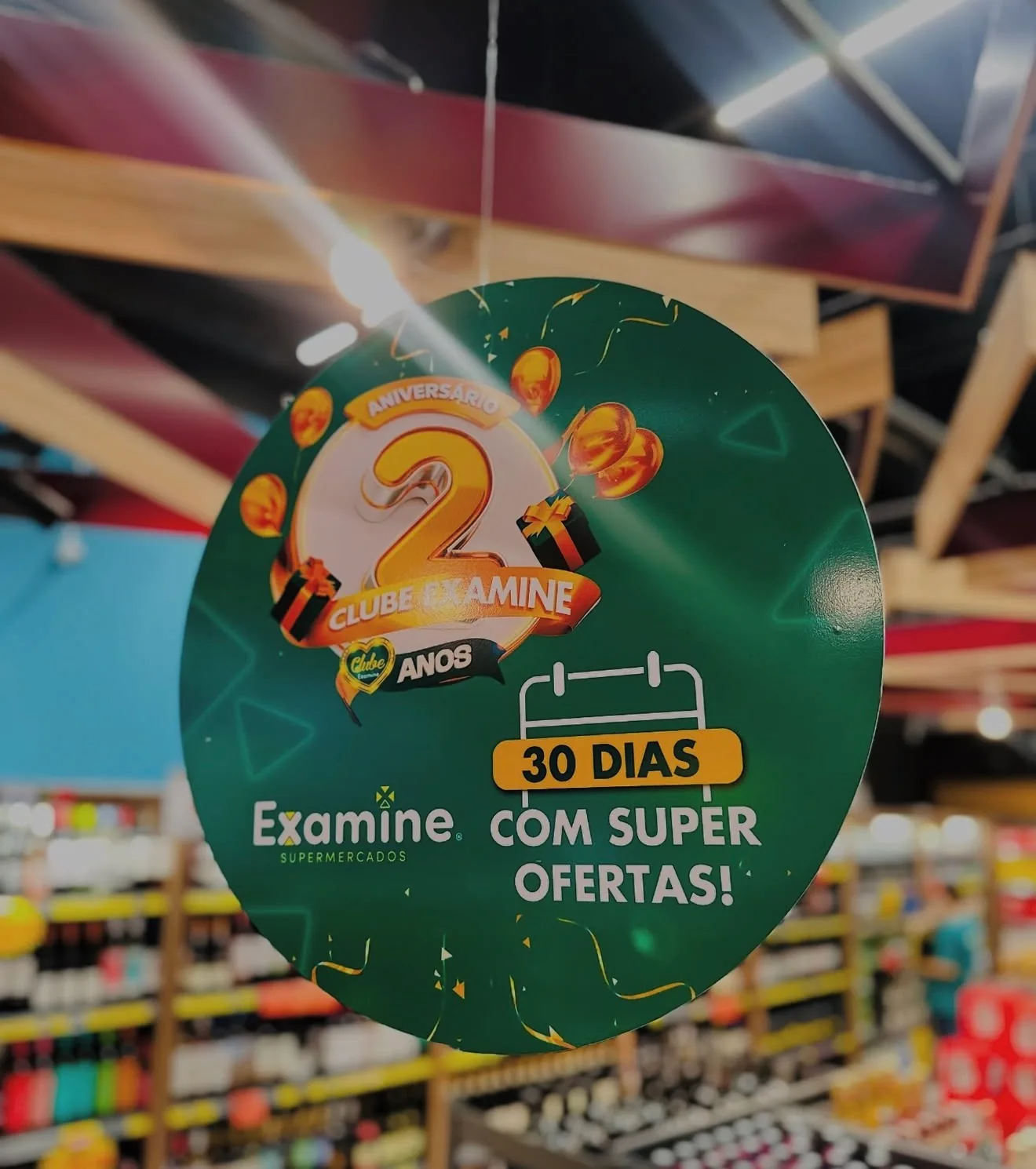 Placa suspensa circular do Clube Examine sobre os corredores de um supermercado